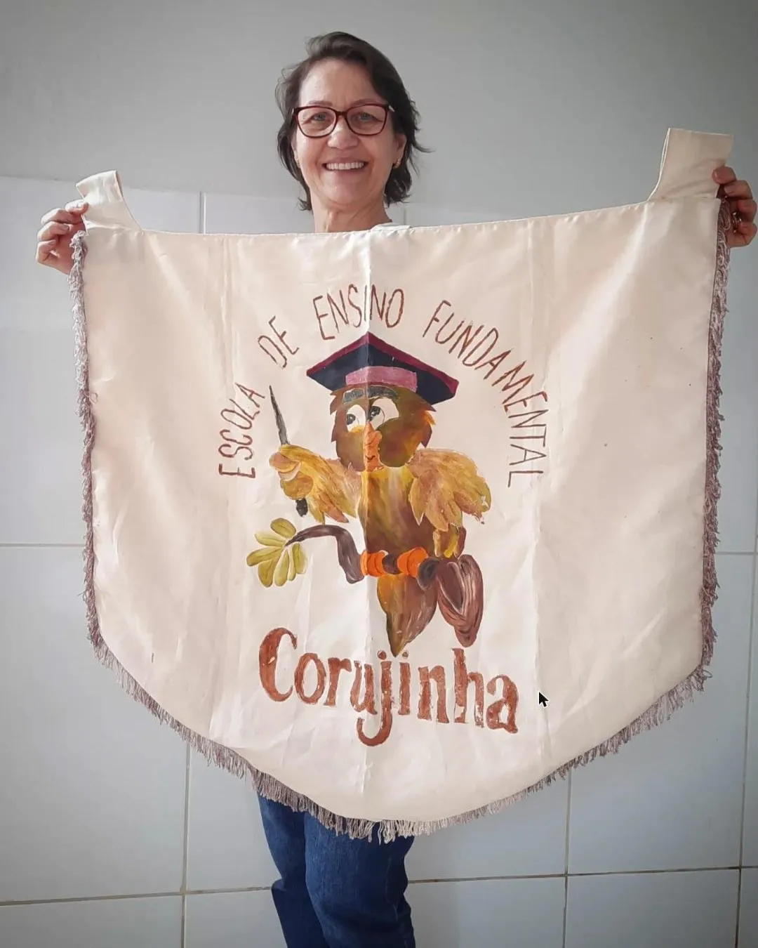 A diretora Ana segurando a flâmula antiga da Escola Corujinha
